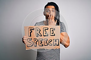 Young african american man with dreadlocks holding banner with free speech message protest cover mouth with hand shocked with