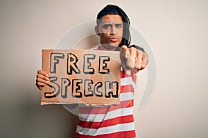 Young african american man with dreadlocks holding banner with free speech message protest pointing with finger to the camera and