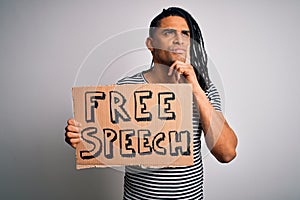 Young african american man with dreadlocks holding banner with free speech message protest serious face thinking about question,