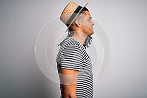 Young african american man with dreadlocks on vacation wearing striped t-shirt and hat looking to side, relax profile pose with