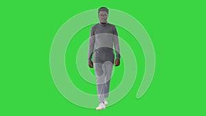 Young african american man in grey casual clothes walking towards camera on a Green Screen, Chroma Key.