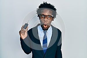 Young african american man holding key of new car scared and amazed with open mouth for surprise, disbelief face