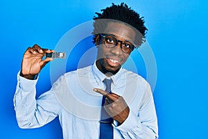 Young african american man holding ssd memory smiling happy pointing with hand and finger