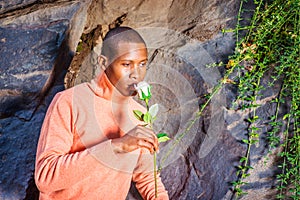 Young African American Man holding white flower, waiting for you