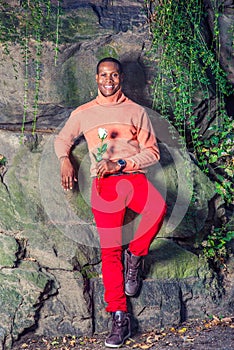 Young African American Man holding white flower, waiting for you