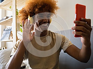 Young African American man at home on the couch making a video call with smartphone