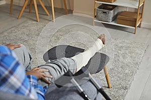 Young African American man with an injured leg and foot sitting on the couch at home