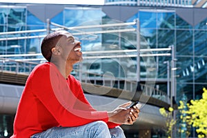 Young african American man laughing outside with mobile phone
