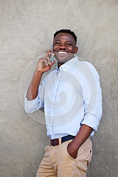 Young african american man leaning against wall talking on cellphone