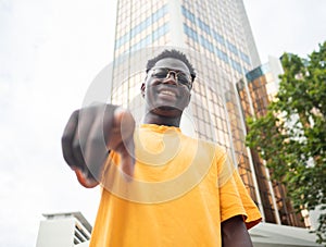 Young african american man looking at camera smiling in a city. Young alternative millennials