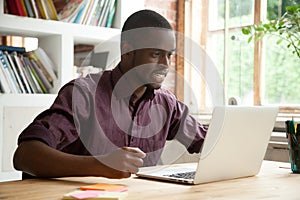 Young african-american man looking at laptop frustrated by bad n