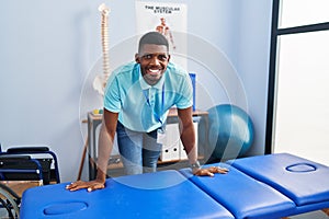 Young african american man physiotherapist smiling confident standing al rehab clinic