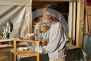Young African American man refinishing wooden furniture