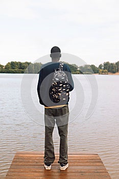 Young African American Man relaxing at Park near lake.