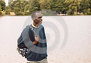 Young African American Man relaxing at Park near lake.