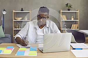 Young african american man sitting at desk working on laptop computer from home
