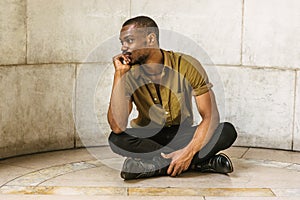 Young African American Man sitting on ground in New York, thinking