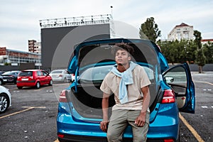 Young african american man sitting in open car trunk