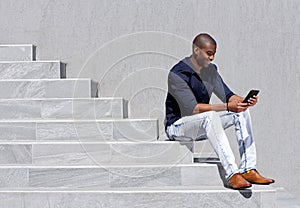 Young african american man sitting on steps using tablet