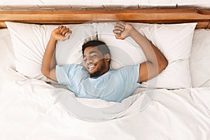 Young african-american man sleeping in bed top view