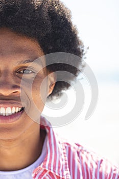 A young African American man smiles brightly outdoors at the beach, unaltered