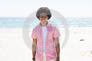 A young African American man smiles brightly on a sunny beach, unaltered