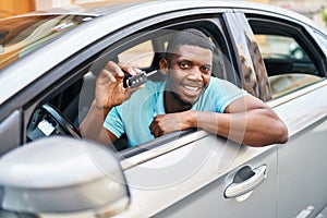 Young african american man smiling confident holding key of new car at street