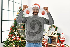 Young african american man smiling happy holding christmas balls at home