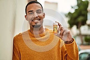 Young african american man smiling happy holding pills at the city