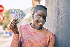 Young african american man smiling happy holding south africa rands at the city photo