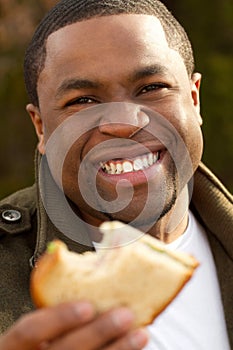 Young African American man smiling outside.