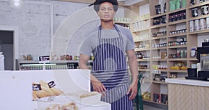 Young African American man stands confidently in a bakery, with copy space