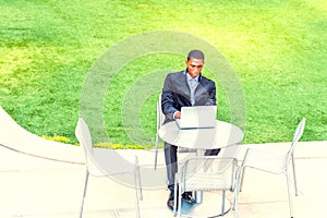 Young African American Man studying on laptop computer at green