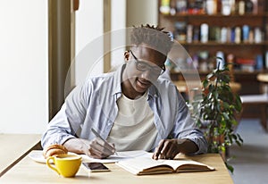 Young African American man studying in modern cafe