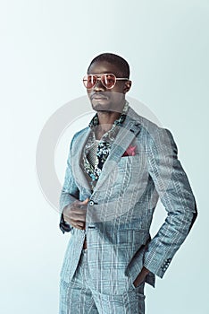 Young african american man in stylish suit and sunglasses, posing with hand in pocket,