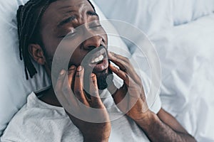 African american man suffering from jaw pain in bedroom photo