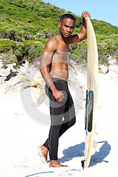 Young african american man with surfboard at the beach