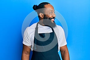 Young african american man tattoo artist wearing professional uniform and gloves looking to side, relax profile pose with natural