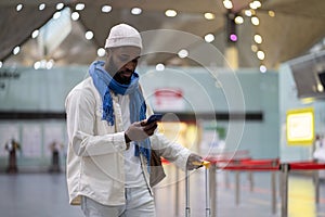 Young African American man traveler using smartphone while waiting to check in airport terminal