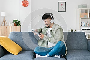 Young african american man using digital device relaxing on sofa at home