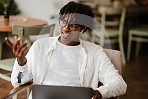 Young african american man using laptop and earbuds in cafe indoors