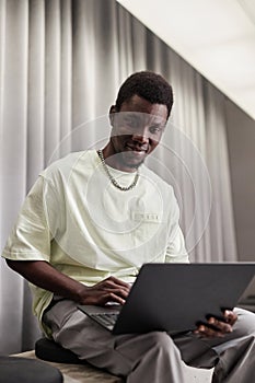 Young African American Man Using Laptop in Office Lounge