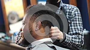 Young African-American man visiting barbershop for haircut