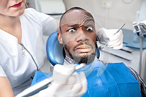 Young african-american man visiting dentist`s office, looks scared