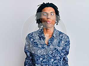 Young african american man wearing 80s style shirt making fish face with lips, crazy and comical gesture