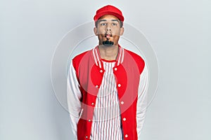 Young african american man wearing baseball uniform making fish face with lips, crazy and comical gesture