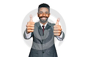 Young african american man wearing business clothes approving doing positive gesture with hand, thumbs up smiling and happy for