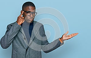 Young african american man wearing business clothes and glasses confused and annoyed with open palm showing copy space and