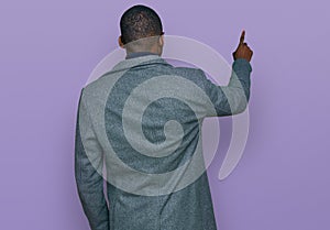 Young african american man wearing business clothes and glasses posing backwards pointing ahead with finger hand