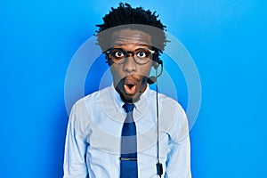 Young african american man wearing call center agent headset scared and amazed with open mouth for surprise, disbelief face